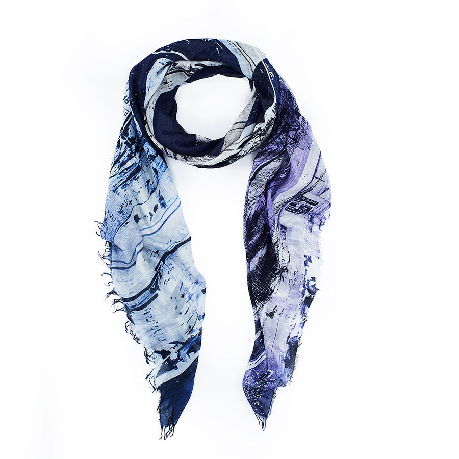 The Hungry for Hope Blues by SUZI ROHER is a lightweight, rectangular scarf with a blue and purple abstract print, frayed edges, and an airy texture—perfect for adding effortless confidence to any outfit.