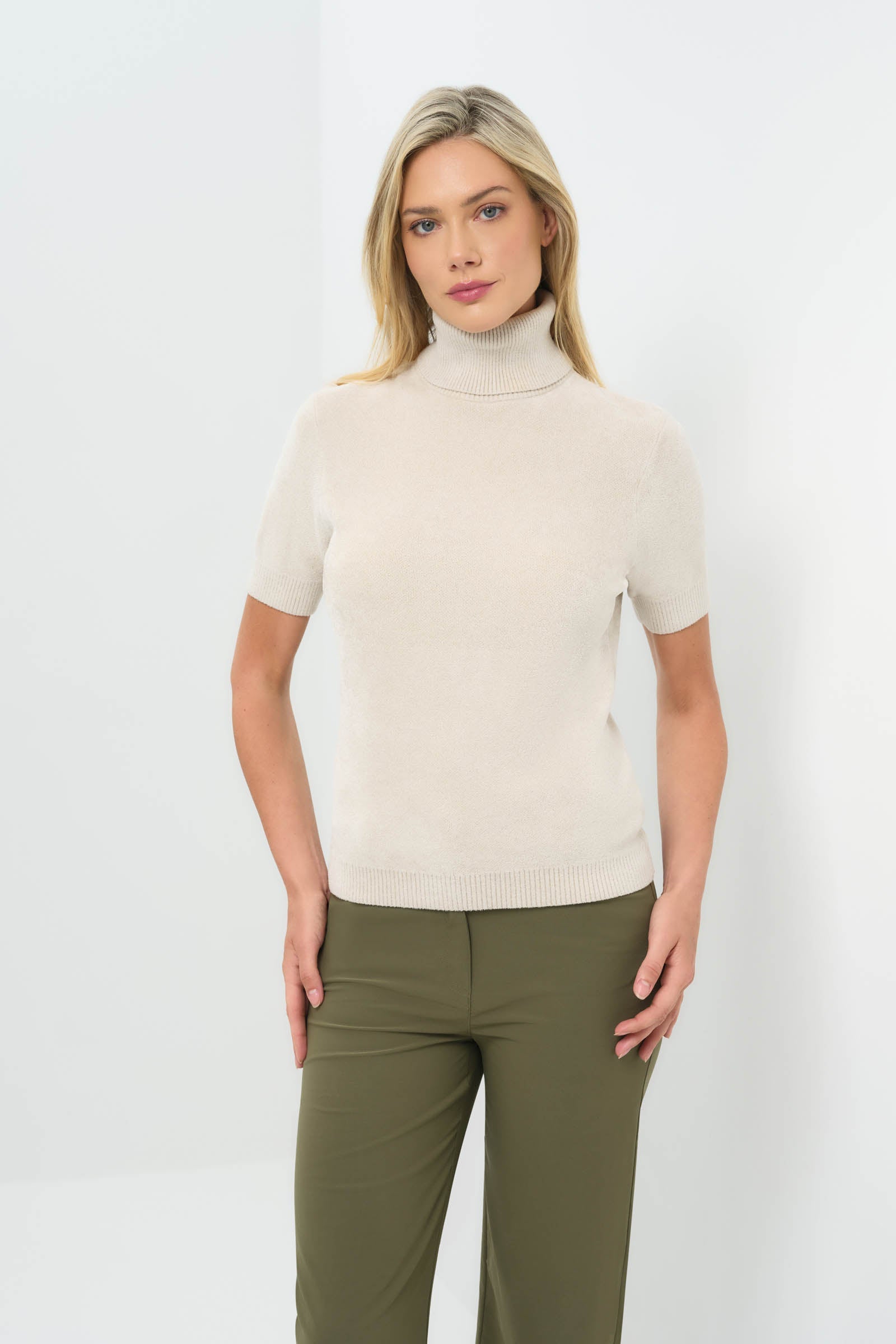 Front view of stone turtleneck short-sleeve top paired with olive green pants.