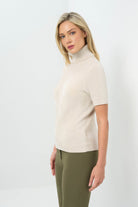 Side view of stone turtleneck short-sleeve top paired with olive green pants.