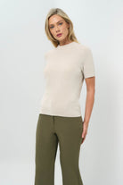 Side view of stone removable turtleneck short-sleeve top paired with olive green pants.