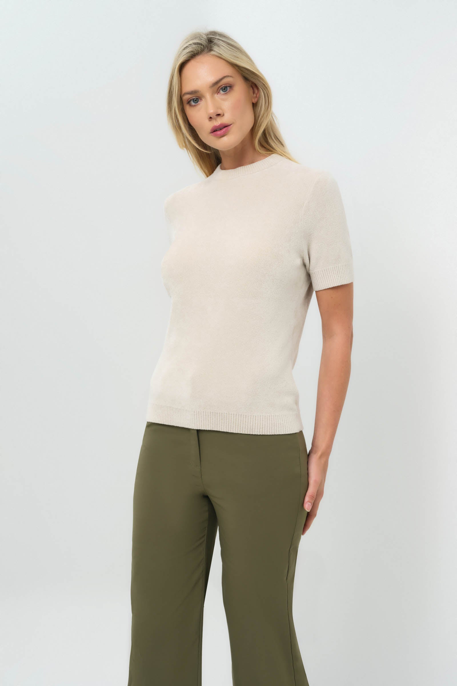 Side view of stone removable turtleneck short-sleeve top paired with olive green pants.
