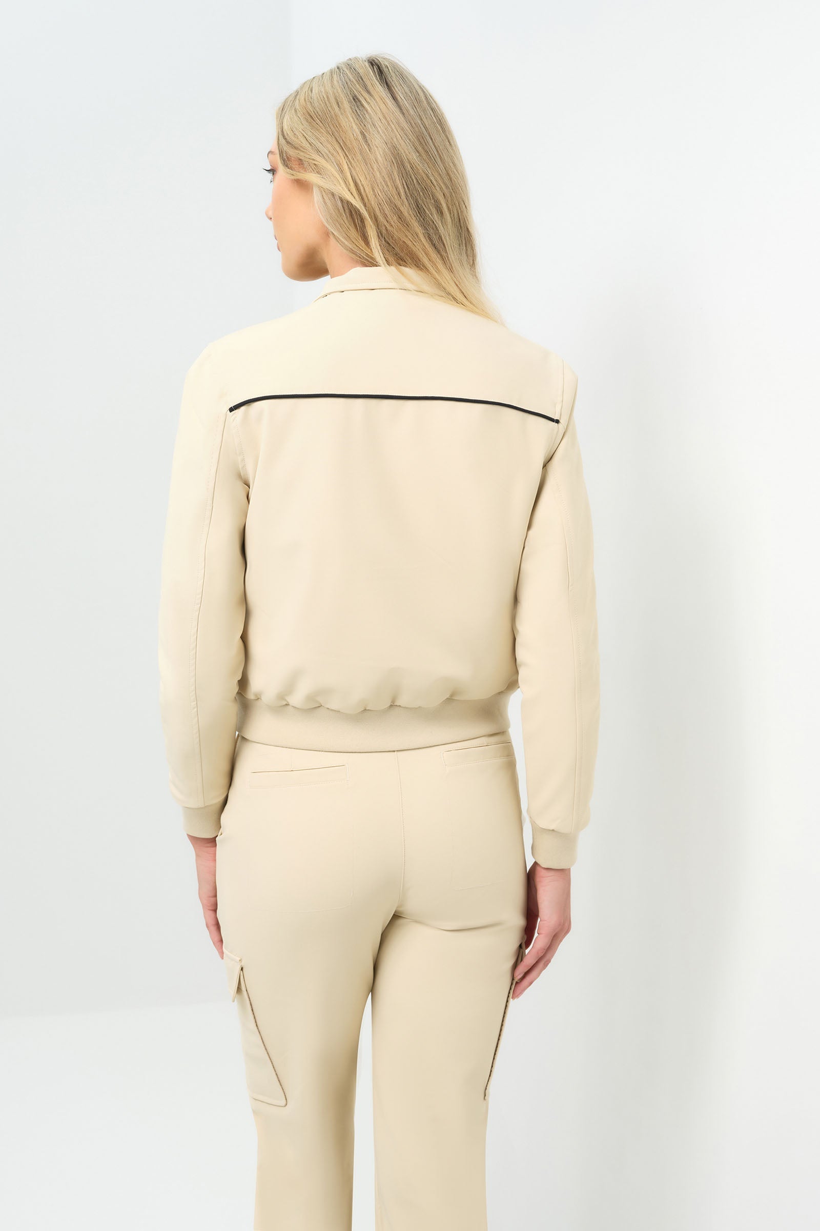 Back view of cream bomber jacket with black pinstripe detailing zipped up to collar