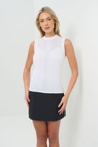 Front view Sleeveless white mock-neck knit top featuring delicate detailing across the upper chest and a vertical textured stripe down the center front. Fitted silhouette for a sleek, polished look.