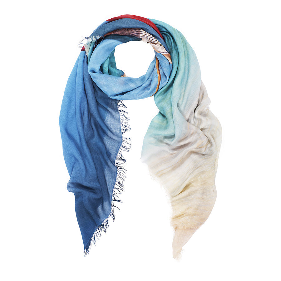 The SUZI ROHER "Barefoot On The Beach" scarf features a lightweight design with a gradient from deep blue to cream, turquoise accents, and soft fringe edges—perfect for the beach.