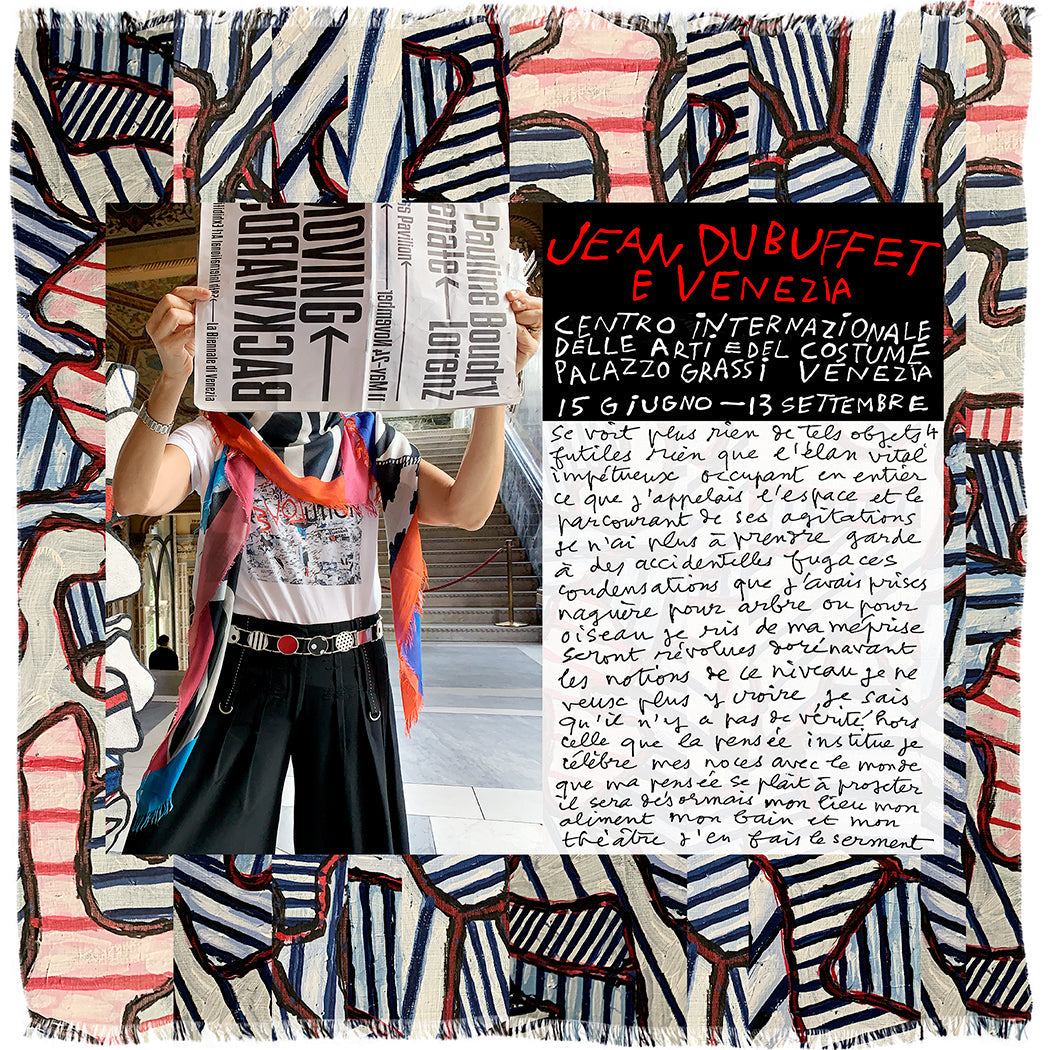A person holds SUZI ROHER's "Dubuffet" poster, hiding their face, against a wall. The image features an abstract, colorful textile border with handwritten exhibit details and notes on artistic creation in Venice, Made in Italy.