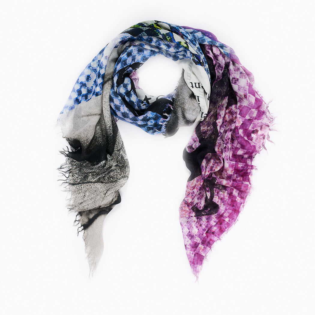 The SUZI ROHER Syntony is a lightweight, rectangular modal silk scarf made in Italy with frayed edges, featuring a blue, purple, black, and white checkered pattern with faint text. Displayed against a white background.