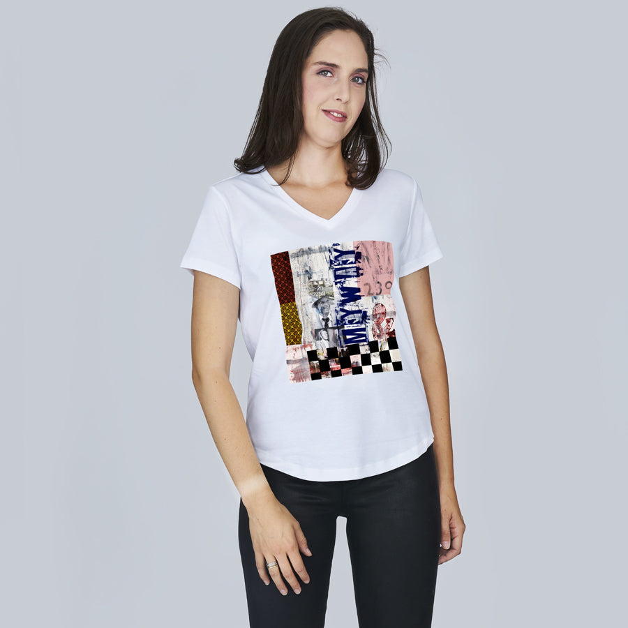Woman with long brown hair wears SUZI ROHER’s The Viv graphic cotton t-shirt and black pants, standing against a light gray background, looking at the camera with a slight smile.