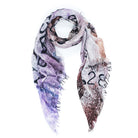 The SUZI ROHER Love Index Blush is a lightweight modal silk scarf with frayed edges, showcasing abstract patterns and bold black numbers, artfully styled in a loose loop on a white background.