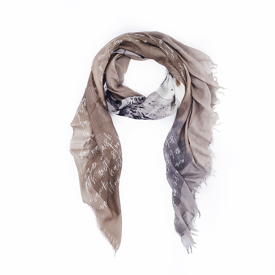 The Surfer Girls scarf by SUZI ROHER is a lightweight, rectangular accessory in neutral brown, beige, and gray tones with white script and a subtle mountain print, crafted in Italy from luxurious modal silk with frayed edges.