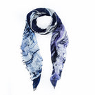 The Hungry for Hope Blues by SUZI ROHER is a lightweight, rectangular scarf with a blue and purple abstract print, frayed edges, and an airy texture—perfect for adding effortless confidence to any outfit.