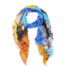 The Kim Kiss Kiss scarf by SUZI ROHER features abstract patterns in blue, orange, yellow, and green with black sketches and red text. Made in Italy from modal silk, it has frayed edges for an artistic, casual look.