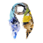 The SUZI ROHER "Cheek To Cheek" scarf is a lightweight, colorful silk piece with frayed edges and an abstract blue, yellow, green, and neutral design, partial white text, and a tribute to Fred Astaire’s Top Hat style.