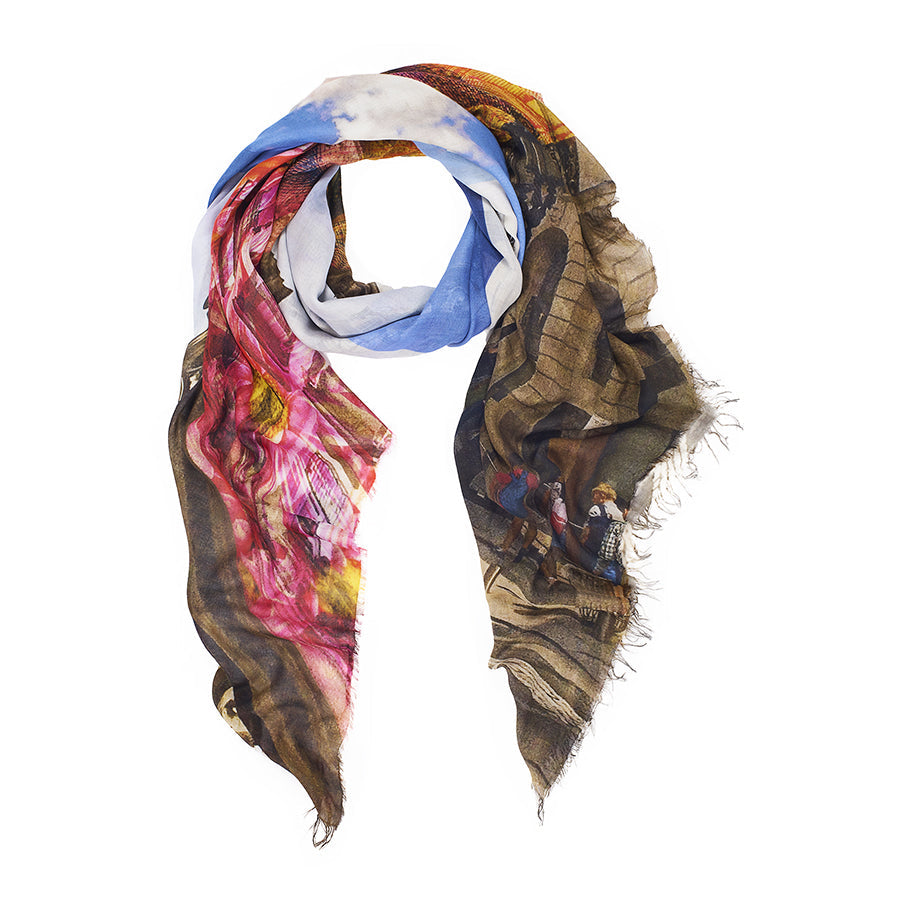 The SUZI ROHER Kim Cross Walk scarf features vibrant blue, pink, brown, and white prints with mixed patterns and images on luxurious modal silk blanket material, finished with frayed edges for a soft, casual drape.