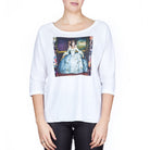 A woman stands against a white background wearing SUZI ROHER’s The Bailey—a white, boxy-cut tee with a boat neckline, featuring a historical painting print of a woman in a blue dress on the front.