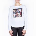 A woman wearing SUZI ROHER's "The Catherine"—a long-sleeve white shirt featuring a colorful, Renaissance-inspired abstract graphic—paired with black pants, stands against a plain white background. Her face is partially out of frame.