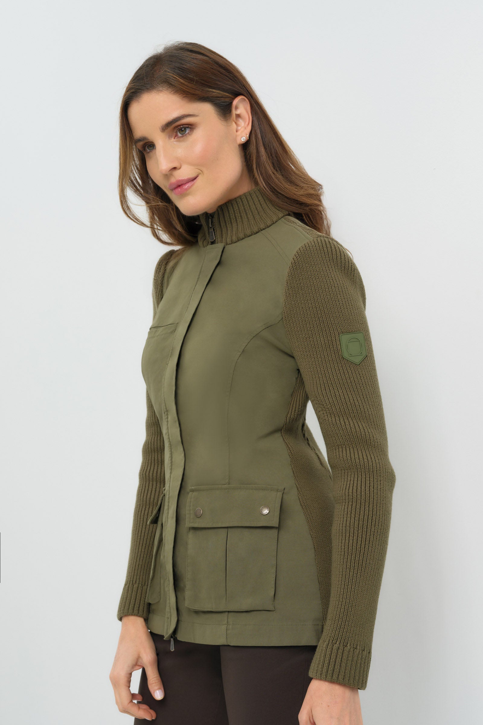 Side view of olive green jacket featuring front pockets and knitted sleeves.
