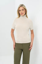 Front view of stone turtleneck short-sleeve top paired with olive green pants.