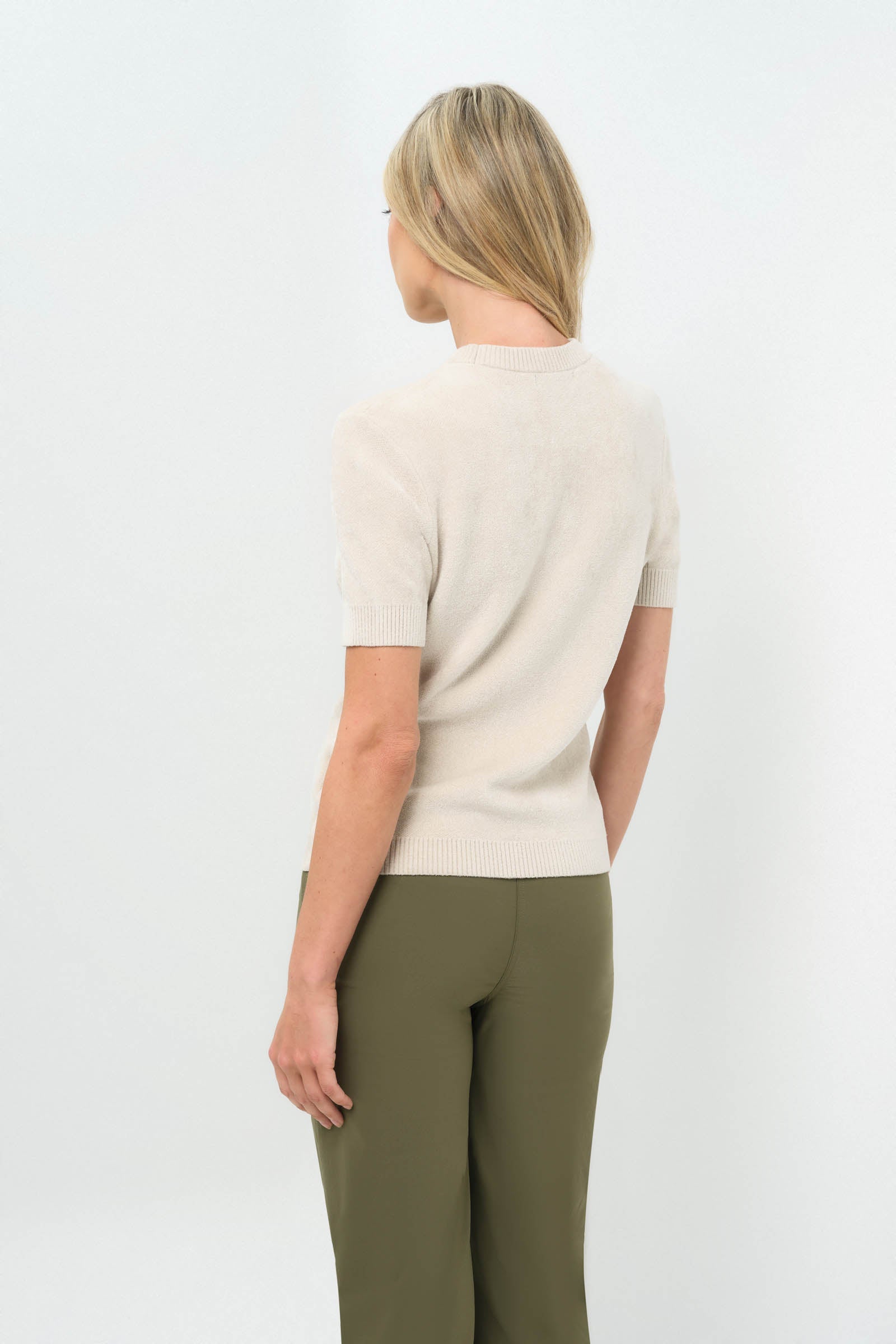 Back view of stone turtleneck short-sleeve top paired with olive green pants.