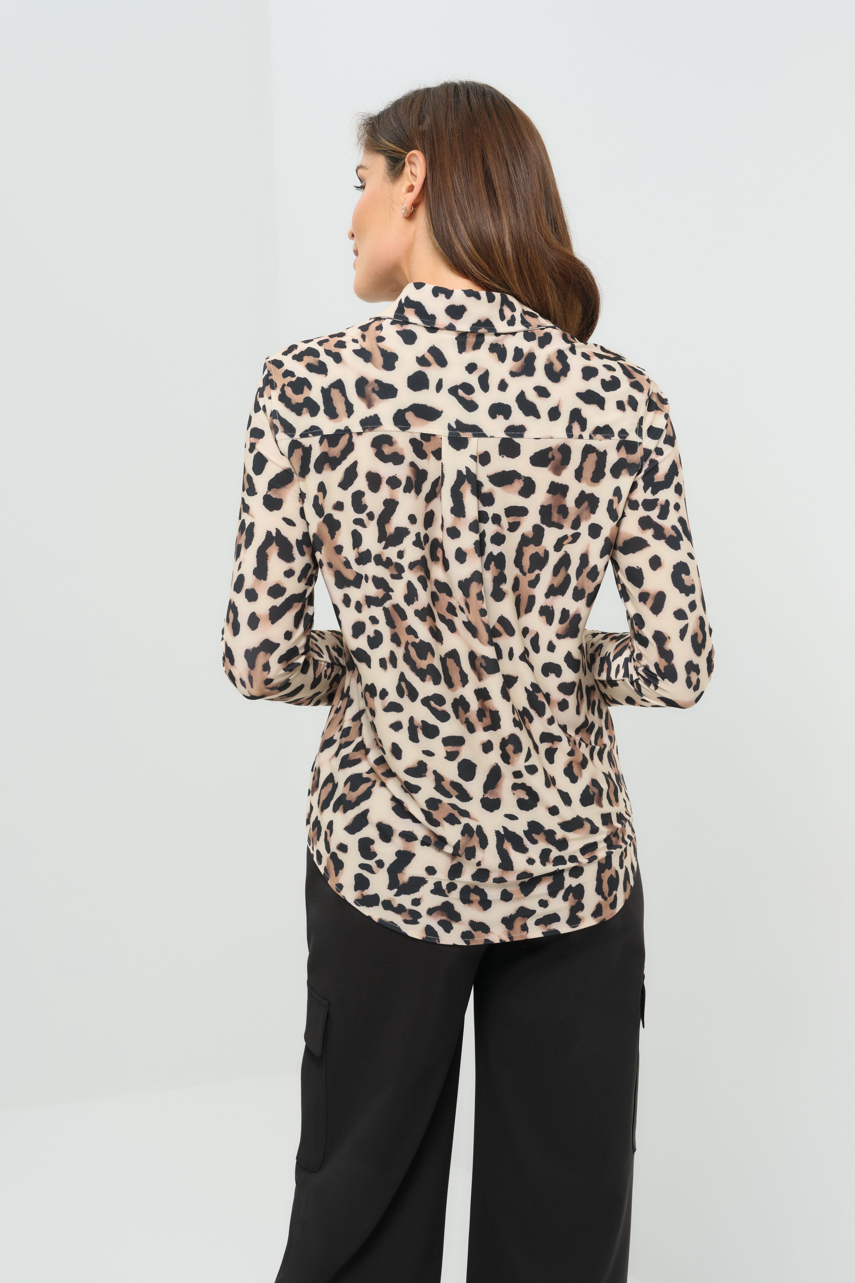 Back view cheetah-print button-down blouse with a classic collar and long sleeves, paired with black utility-style cargo pants featuring flap pockets.