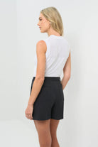 Side view of the black skort with a white stripe on the side, paired with a white short-sleeve top.