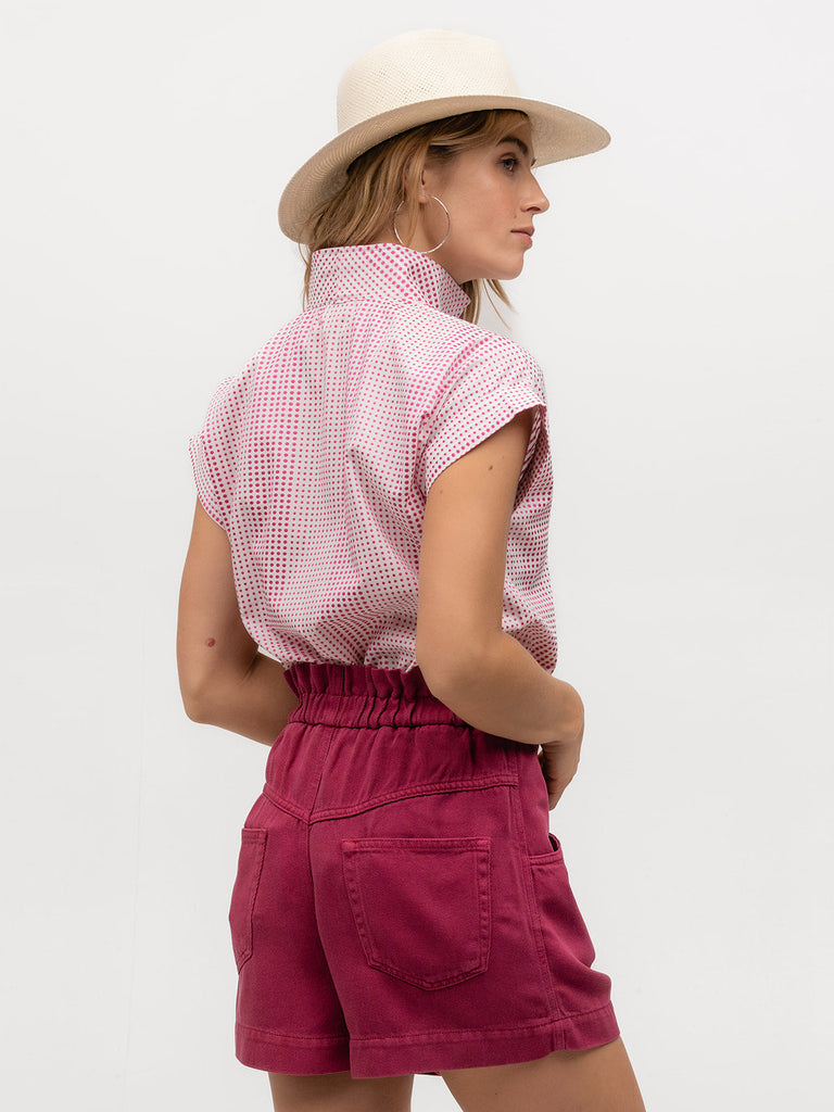 Woman wearing a luxurious magenta and white cap sleeve shirt with magenta shorts