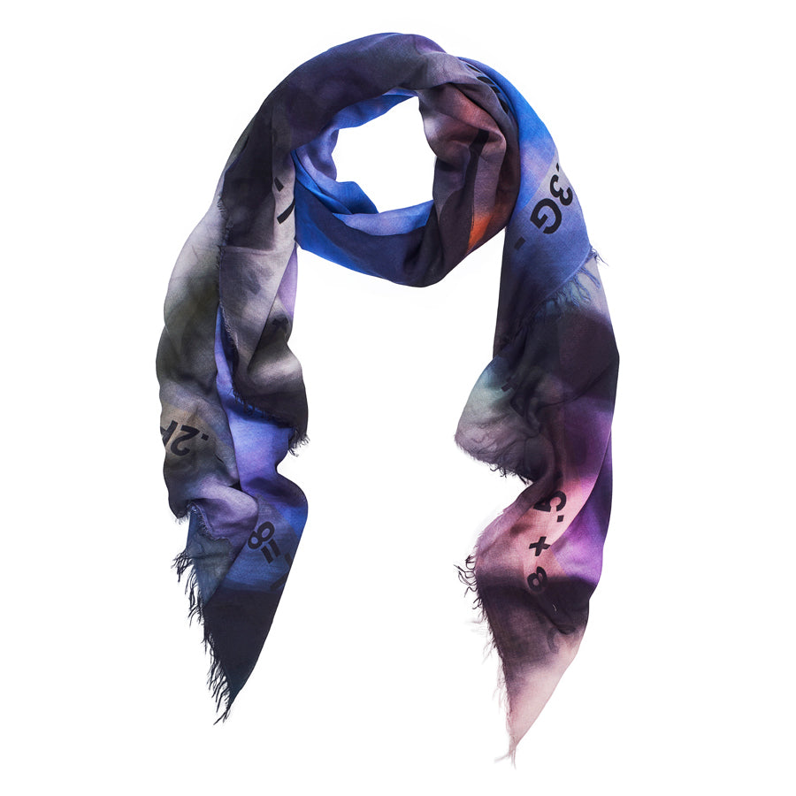 The "Love Always" scarf by SUZI ROHER is a lightweight luxury accessory in soft modal silk, with frayed edges and a gradient of blue, purple, black, and pink decorated with scattered numbers and mathematical symbols.
