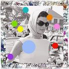 A stylish woman in the SUZI ROHER "Because We Love You" modal silk scarf and sunglasses stands by vintage cars, surrounded by a crowd. Colorful dots and a handwriting-style border echo timeless Jackie Kennedy elegance.