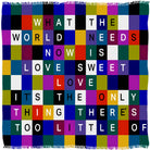 The “Sweet Love” scarf by SUZI ROHER features a vibrant grid design, each square displaying a letter from the iconic phrase: WHAT THE WORLD NEEDS NOW IS LOVE SWEET LOVE.