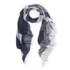 The SUZI ROHER "Electric Love- B&W" scarf features a loosely coiled geometric pattern in dark blue, gray, and white with fringe edges, inspired by BØRNS’ “Electric Love,” and is displayed on a white background.