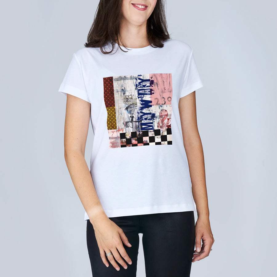 A woman wearing The Niki white t-shirt by SUZI ROHER, featuring a colorful abstract graphic and "ONLY MAYBE" text inspired by My Way, stands against a plain light gray background.