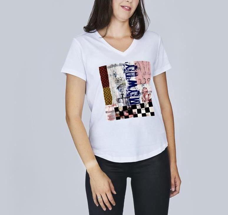 A woman wears SUZI ROHER's The Viv, a white V-neck tee with a multicolored abstract graphic, paired with black pants against a plain light gray background.