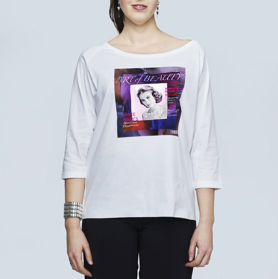 A woman wears SUZI ROHER's The Bailey, an oversized white long-sleeve shirt featuring a colorful vintage magazine cover graphic with a black-and-white woman and "Art of Beauty" text on the front.
