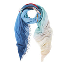 The SUZI ROHER "Barefoot On The Beach" scarf features a lightweight design with a gradient from deep blue to cream, turquoise accents, and soft fringe edges—perfect for the beach.
