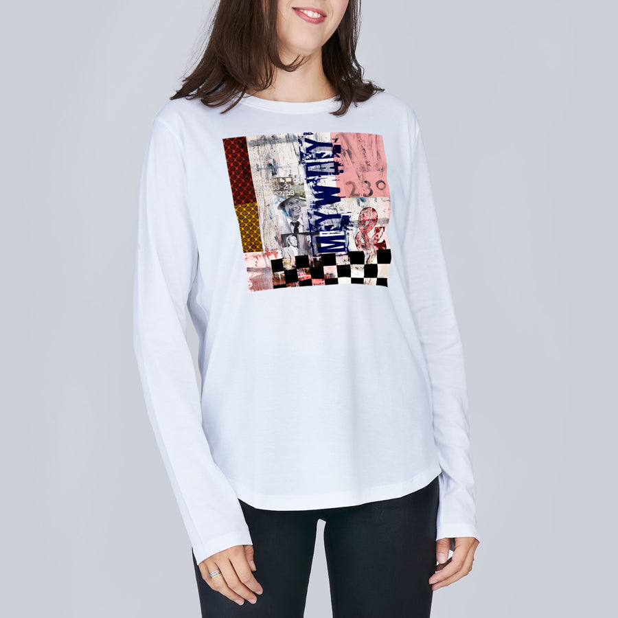 A woman wears The Catherine by SUZI ROHER—a clean-cut crew neck long sleeve tee with a colorful, abstract graphic of checkered and textured patterns—standing against a plain light gray background.