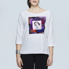 A woman smiles wearing SUZI ROHER’s The Bailey—a white, long-sleeve boxy tee with a colorful square graphic of Grace Kelly, reading "ART of BEAUTY." She accessorizes with earrings and a bracelet.