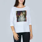 A woman wears The Bailey by SUZI ROHER, a white boxy tee featuring a print of a woman in an ornate 18th-century dress. Its boat neckline pairs with her smile as she stands against a plain background.