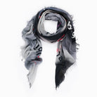 The SUZI ROHER "Lovefest" scarf is a lightweight modal silk accessory with frayed edges, featuring a black, gray, and white gradient and bold black and red letters spelling "love." Shown loosely coiled on a white background.