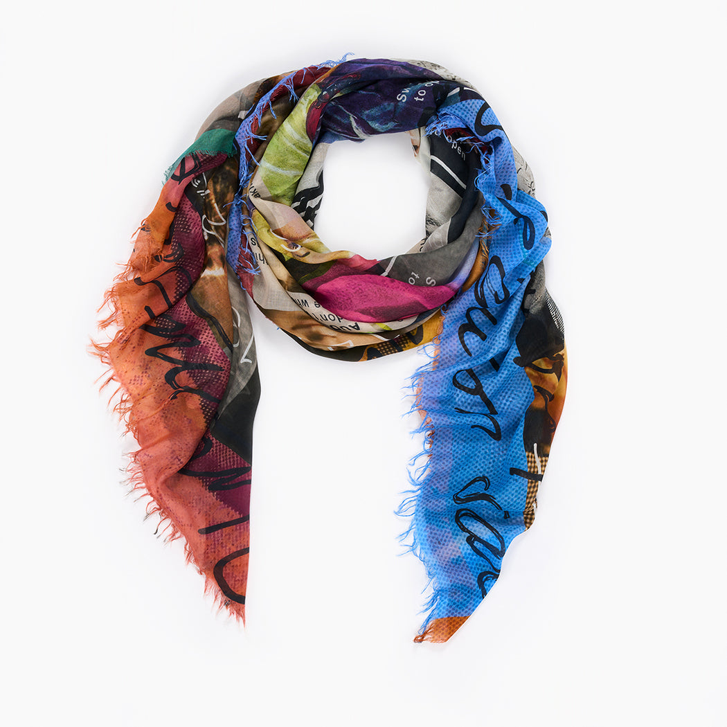 The "Messages" scarf by SUZI ROHER is a colorful, triangular modal silk piece with a frayed edge and abstract blue, orange, green, and black pattern. Made in Italy, it's shown against a white background.